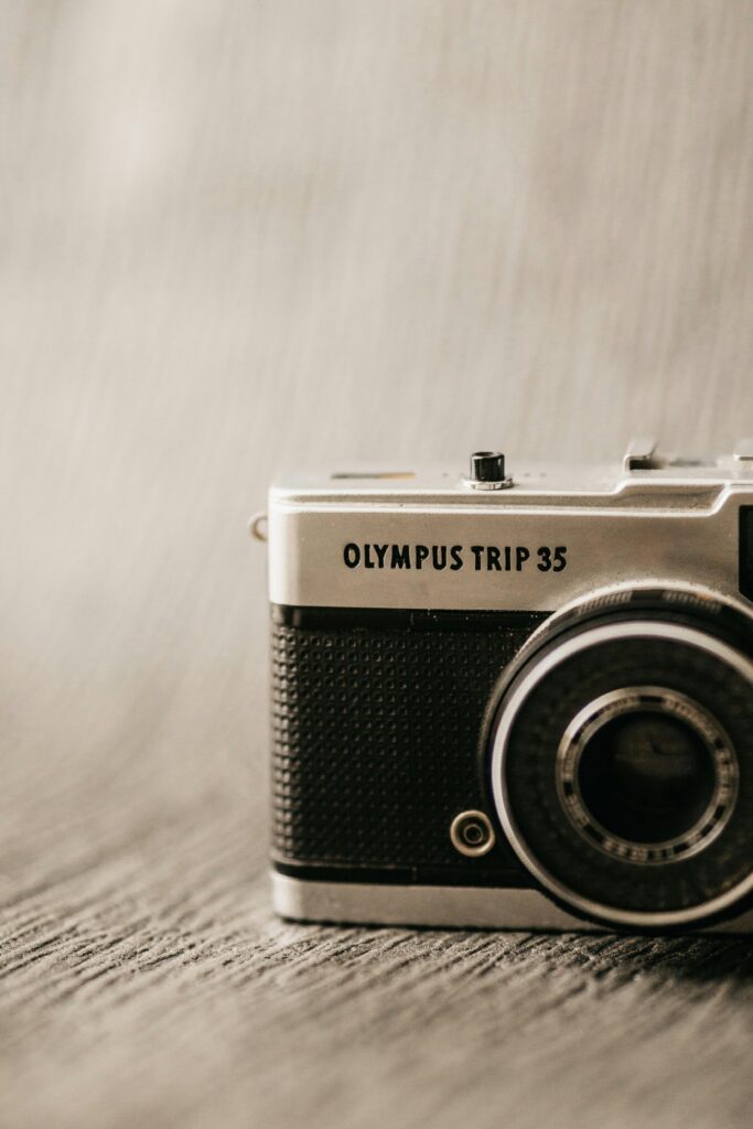 Old compact photo camera with inscription and numbers on metal frame with button on blurred background