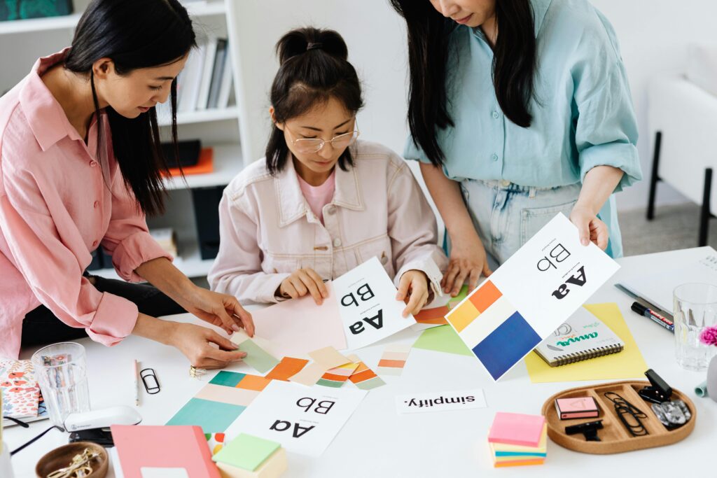 Three women engage in teamwork on a design project, sharing ideas and creativity.